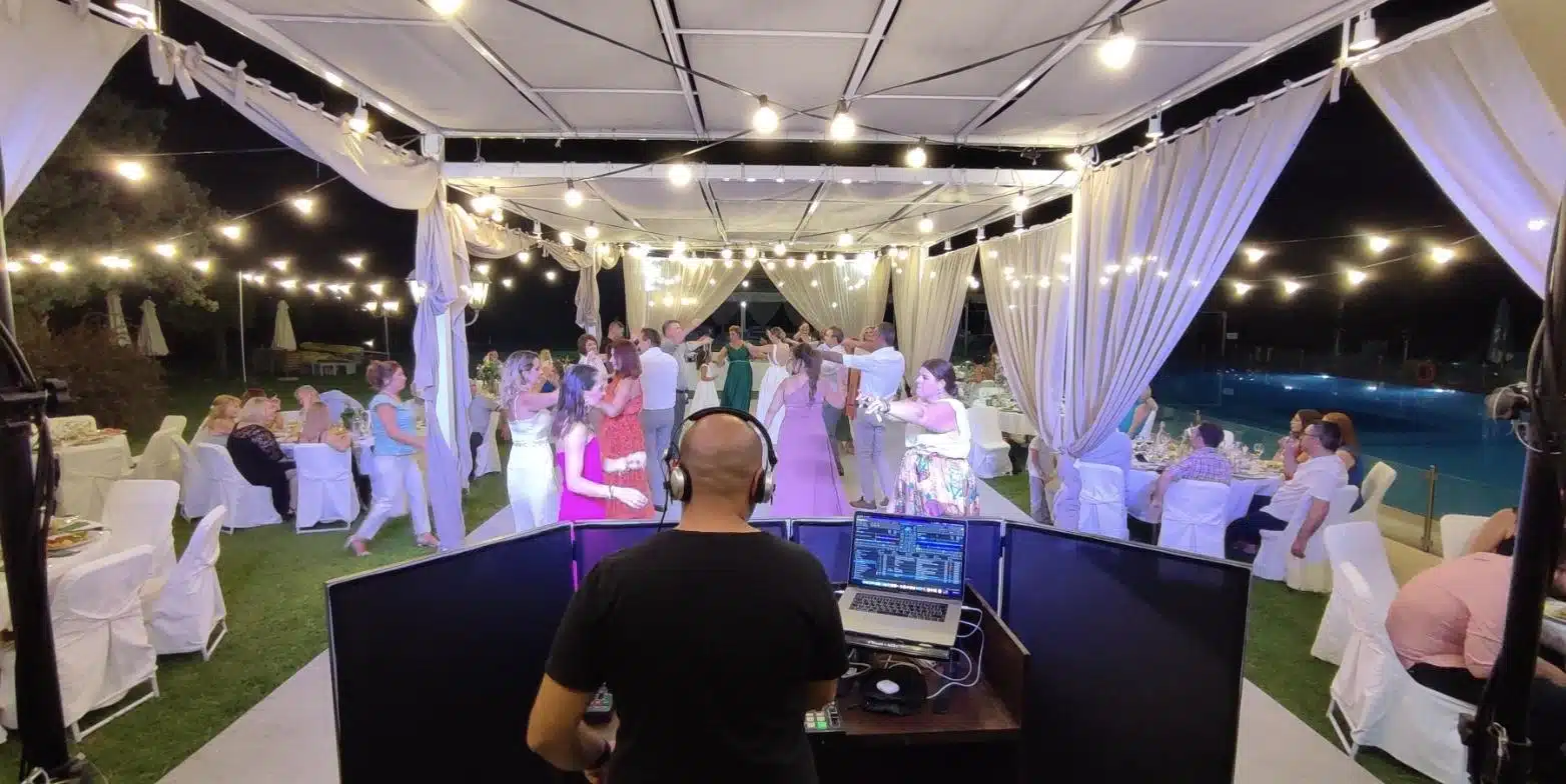 DJ πίσω από την κονσόλα σε υπαίθρια δεξίωση με γεμάτη πίστα