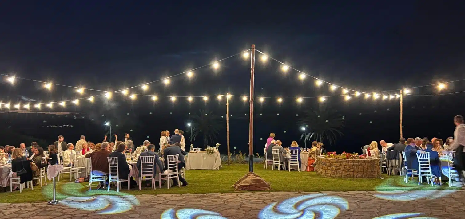 Κρεμαστά string lights πάνω από τραπέζια σε υπαίθριο χώρο εκδήλωσης